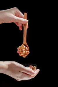 Close-up of hand holding ice cream against black background