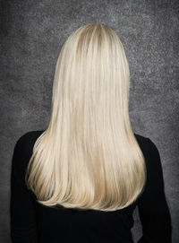 Rear view of woman standing against gray background