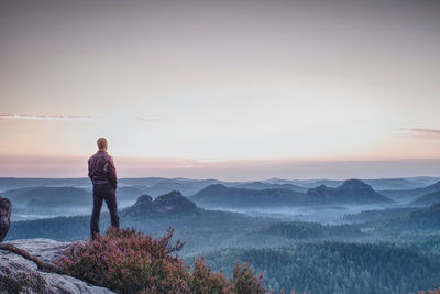 Rear view of man looking at mountains against sky