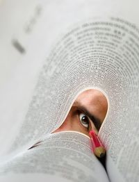 Close-up of man eye seen through book