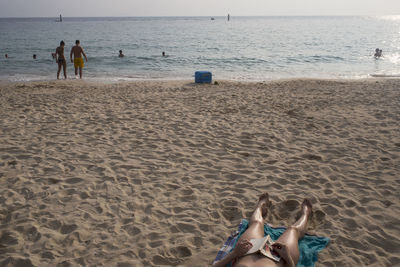 People playing on beach against sky