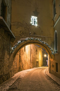 Empty alley amidst buildings in city at night