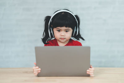 Young woman using laptop while sitting on sofa at home