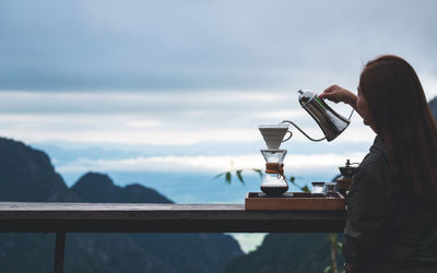 A young asian woman making drip coffee with a beautiful mountain and nature background