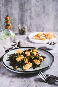 Vegetarian fried tofu and seaweed salad on a plate on the table vertical view