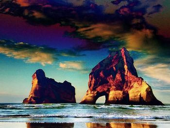 Rock formation on beach against sky during sunset