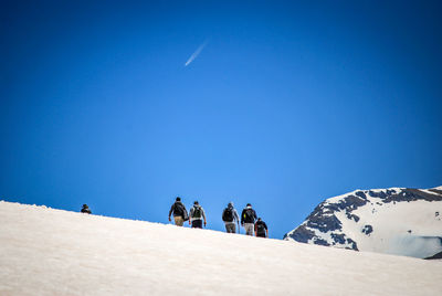 Low angle view of male hikers hiking on snowcapped mountain