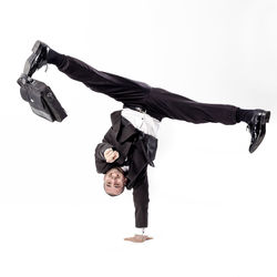 Full length of happy businessman doing handstand against white background