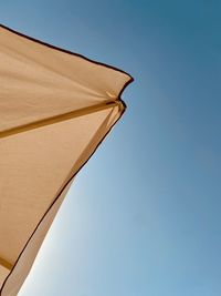 Low angle view of parasol against clear blue sky