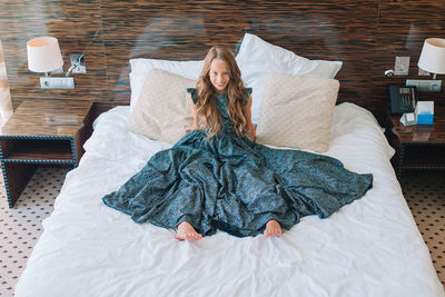 Low section of woman standing on bed at home