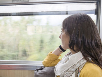 Woman looking through window while sitting at train