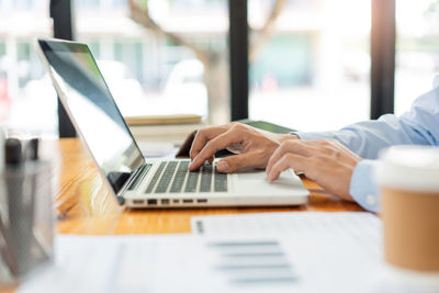 Midsection of businesswoman using laptop on table