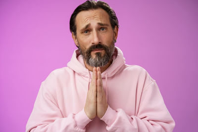 Man pleading against purple background