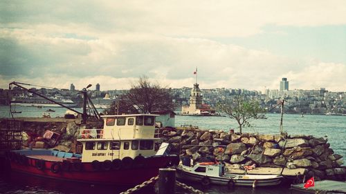 Boats in harbor against cloudy sky