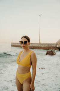 Young woman wearing sunglasses while standing at beach