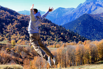 Rear view of person with arms raised in mountains