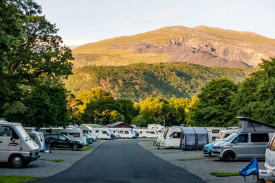 Cars parked in parking lot by mountain against sky