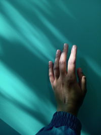 Close-up of human hand by wall during sunny day