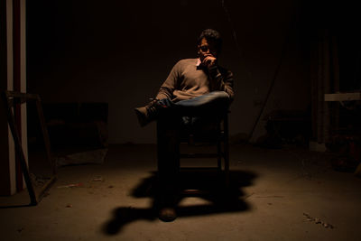 Man sitting on chair with shadow in darkroom