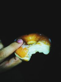 Close-up of hand holding ice cream over black background