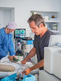 Doctors preparing operating theater for surgery while working in modern hospital together