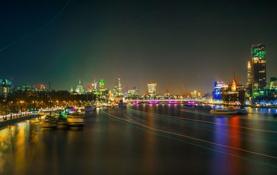 River amidst illuminated cityscape against sky at night