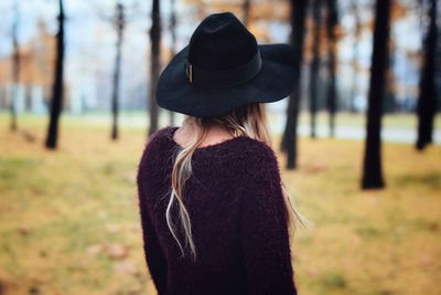 Rear view of woman wearing hat standing against trees