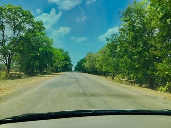 Road amidst trees seen through car windshield