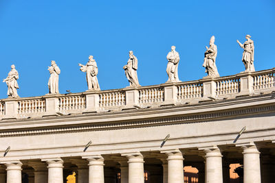 Low angle view of statues against blue sky