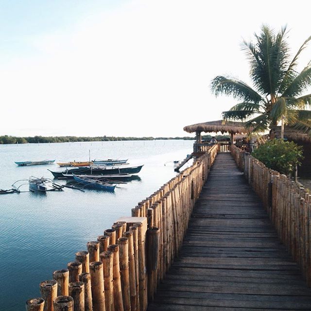 water, the way forward, pier, transportation, clear sky, built structure, nautical vessel, sea, diminishing perspective, architecture, moored, railing, copy space, in a row, boat, sky, tranquil scene, jetty, mode of transport, tranquility