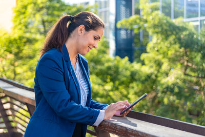 Side view of a smiling young woman using mobile phone