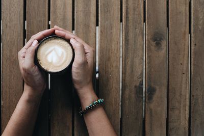 Directly above shot of hand holding coffee cup