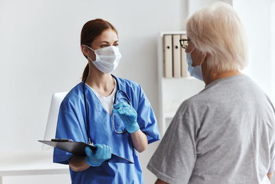 Side view of female doctor holding medicine while standing against white background