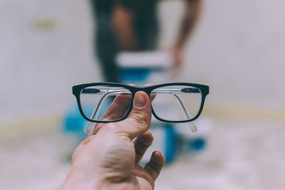 Cropped hand of person holding eyeglasses