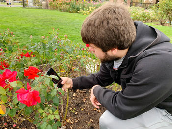 Side view of young man holding flowering plants