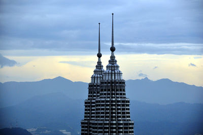 Communications tower in city against sky