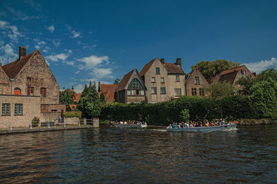 Houses by river and buildings against sky