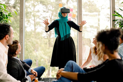 Businesswoman wearing virtual reality simulator during conference with colleagues at convention center