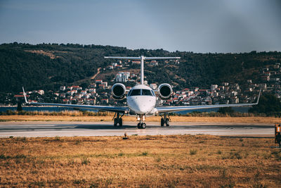 Airplane at airport runway against sky