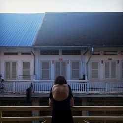 Rear view of woman standing against building