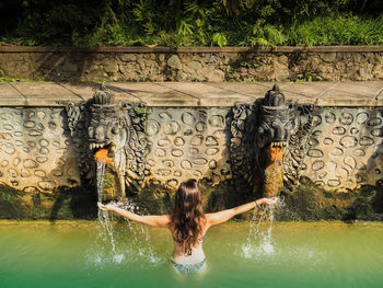 Rear view of woman standing by fountain