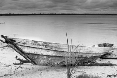 Abandoned boat on beach against sky