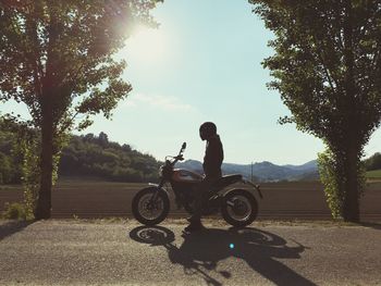 Man riding motorcycle on road against trees