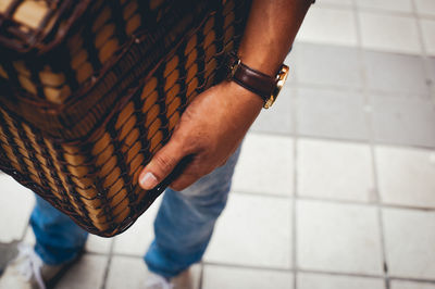 Low section of man holding basket while standing on footpath