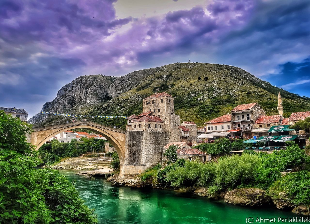 architecture, built structure, building exterior, sky, water, tree, cloud - sky, arch bridge, connection, bridge - man made structure, river, cloud, arch, mountain, waterfront, history, house, cloudy, travel destinations, day