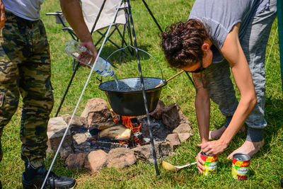 Friends preparing food at campfire