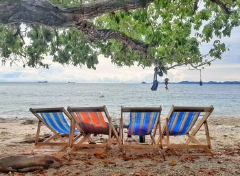 Chairs on beach by sea against sky