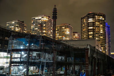 Illuminated buildings in city against sky at night