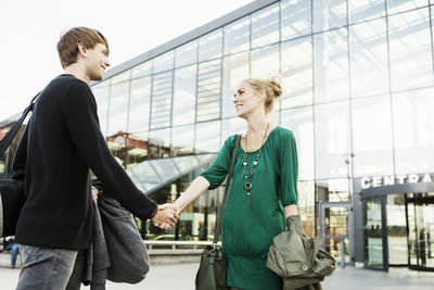 Friends greeting while standing outside railroad station