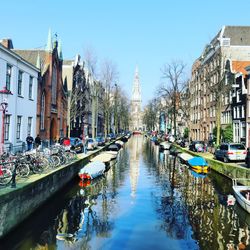 Canal amidst buildings in city against sky